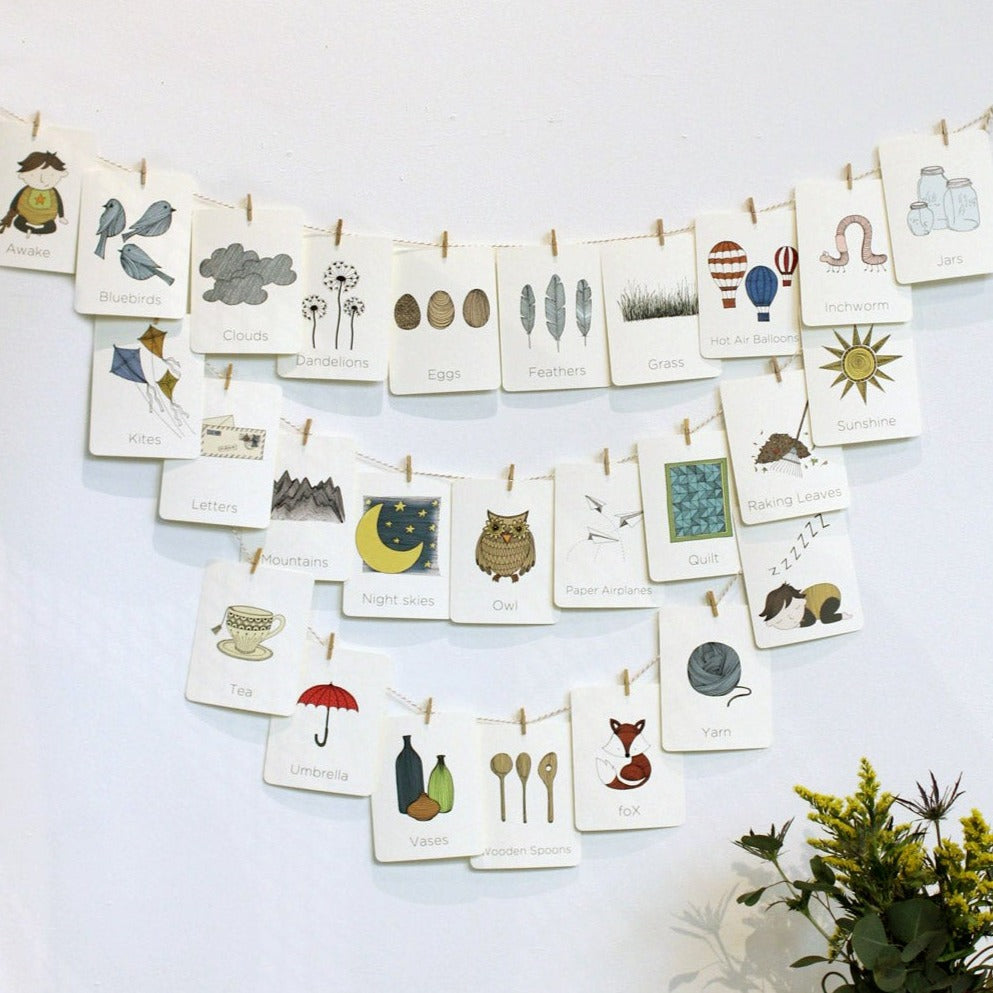 Alphabet cards with adorable imagery attached to string on a nursery wall. 