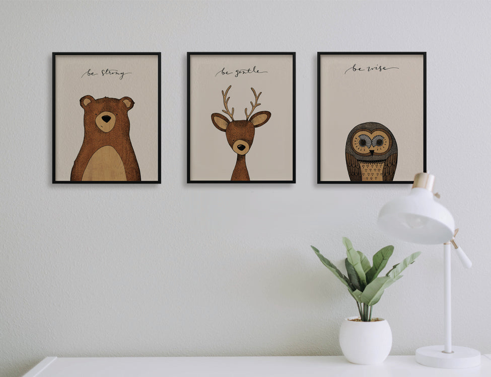 Trio of woodland prints with phrases: Be Strong, Be Gentle, Be Wise over a bear, deer, and owl. Perched above a simple desk